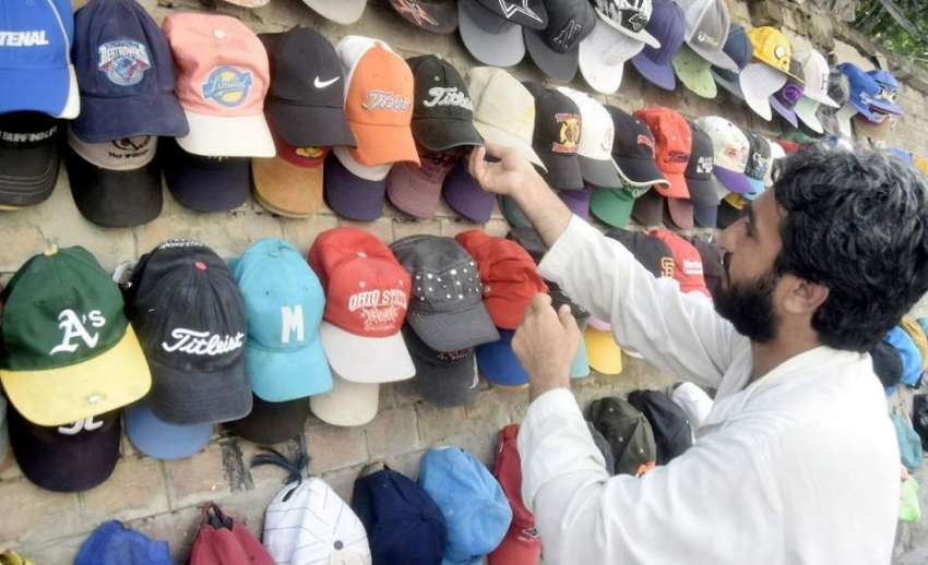 لاہور: ایک شخص دھوپ سے بچنے کے لیے ٹوپی خرید رہا ہے۔