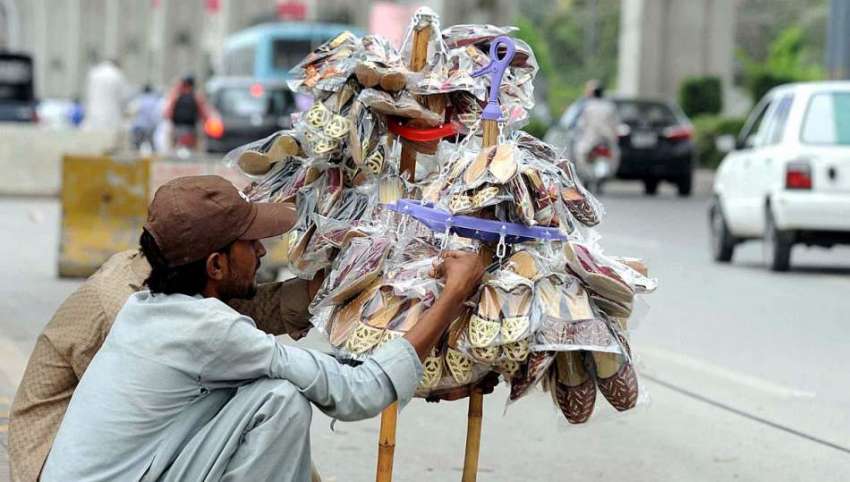 راولپنڈی: محنت کش پھیری لگا کر جوتے فروخت کررہا ہے۔