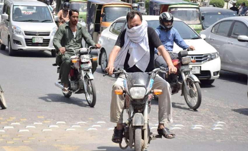 لاہور: ایک موٹر سائیکل سوار گرمی کی شدت سے بچنے کے لیے منہ ..