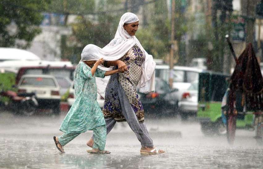 راولپنڈی: بارش کے دوران ایک خاتون اپنی بیٹی کے ساتھ  سڑک ..