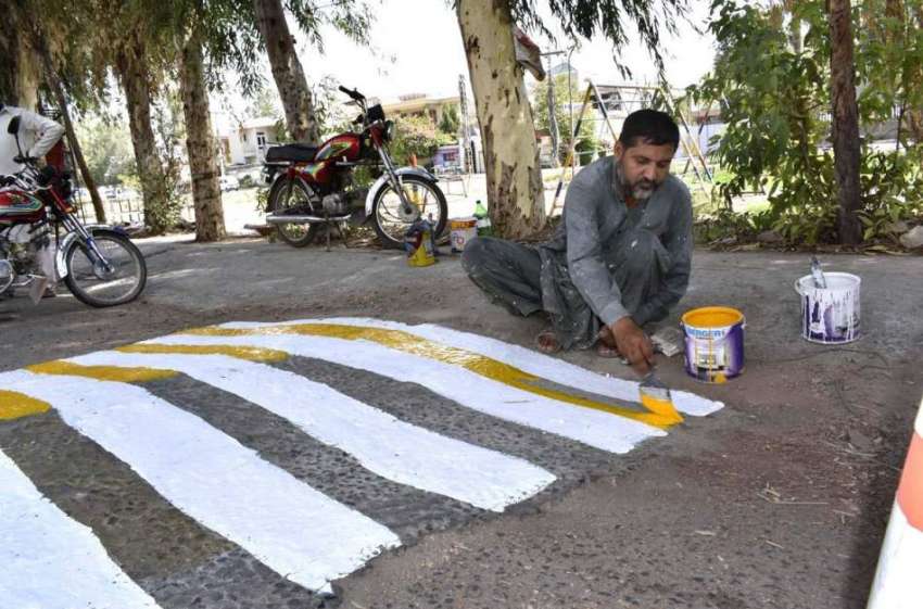 فیصل آباد: مزدور سپیڈ بریکر کو رنگ کرنے میں مصروف ہے۔