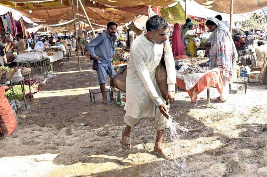 فیصل آباد: کھنوانہ کے بازار میں ایک مزدور پانی بہا رہا ہے۔