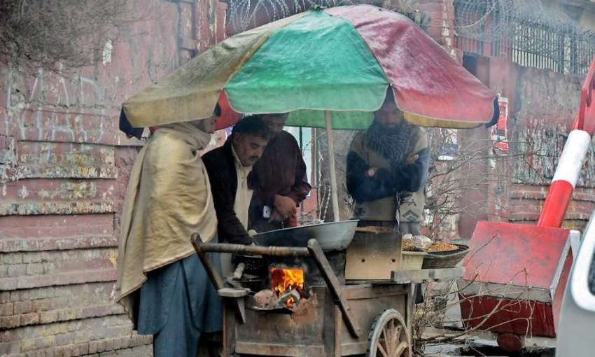 را ولپنڈی: بارش کے دوران شہری ایک ریڑھی بان سے مکئی کے گرم ..
