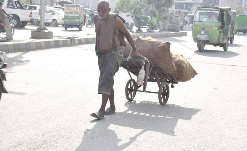 لاہور: ایک بزرگ محنت کش ہتھ ریڑھی پر سامان رکھے جا رہا ہے۔
