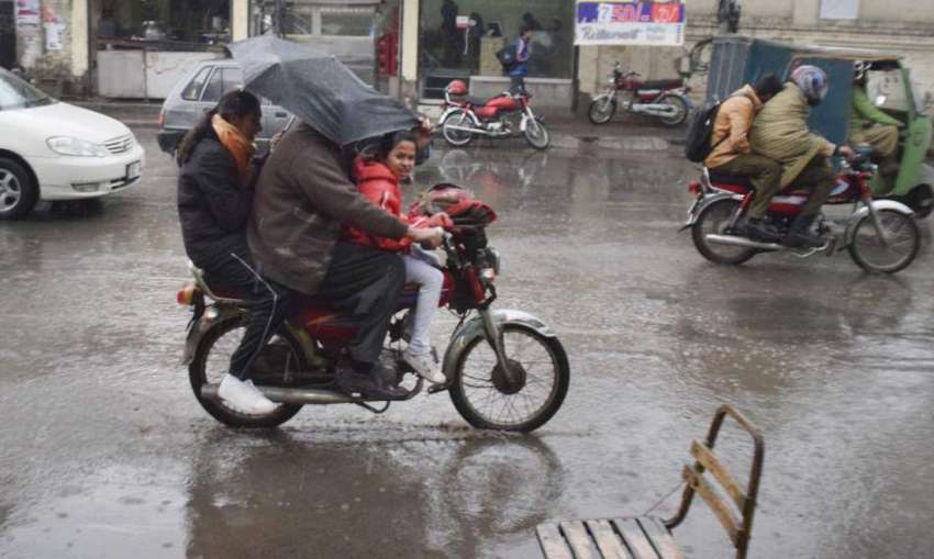لاہور: موٹر سائیکل سوار بچوں کو سکول سے لیکر بارش سے بچنے ..