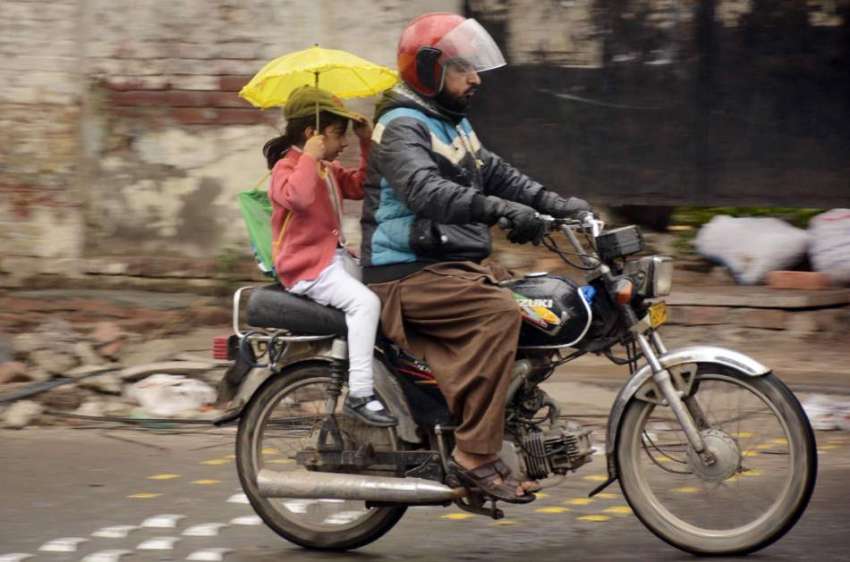 لاہور: موٹرسائیکل سوار بارش کے دوران اپنی منزل کی جانب رواں ..