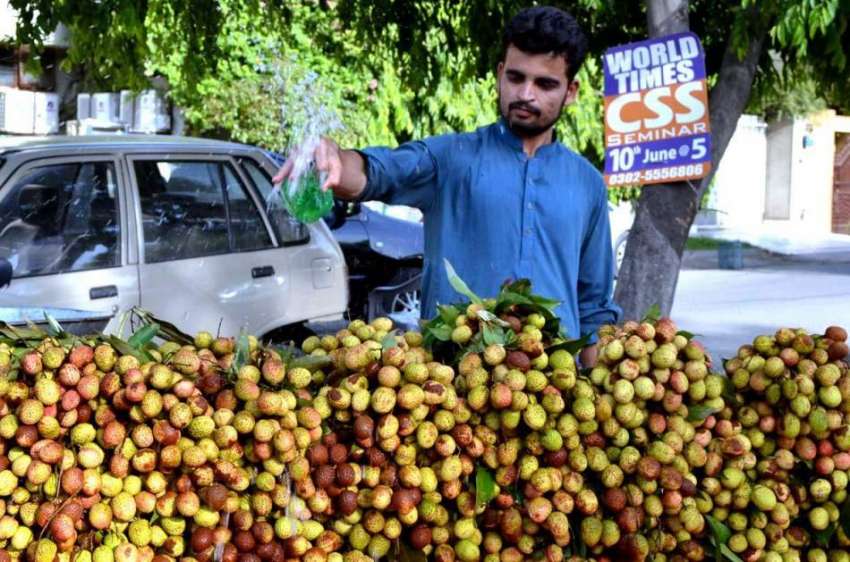 لاہور: ریڑھی بان موسمی پھل (لیچی) کو تازہ رکھنے کے لیے پانی ..