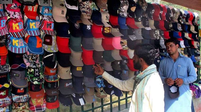 بہاولپور: ایک شہری سڑک کنارے لگے سٹال سے ٹوپی پسند کررہا ..