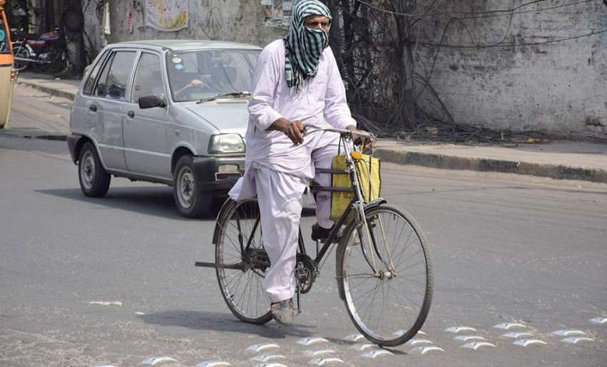 لاہور: ایک سائیکل سوار شہری گرمی کی شدت سے بچنے کے لیے منہ ..