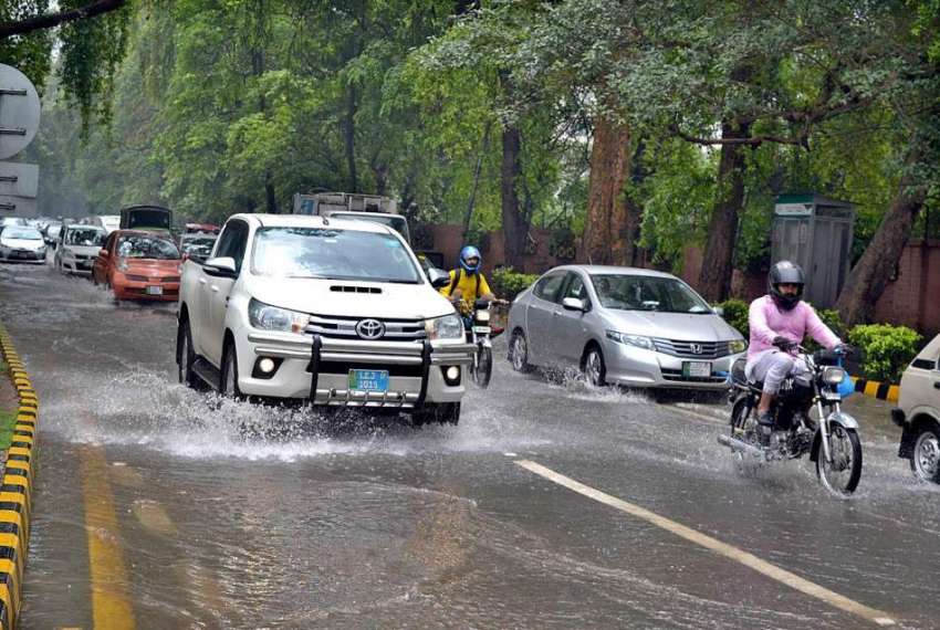 لاہور: موسلا دھار بارش کے بعد جمع شدہ پانی سے گاڑیاں گزر ..