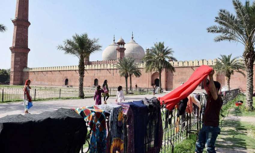 لاہور: ایک نوجوان کپڑے خشک کرنے کے لیے بادشاہی مسجد کے جنگلے ..