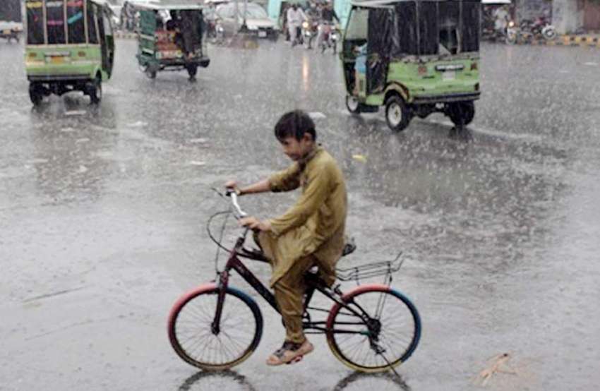 لاہور:ایک سائیکل سوار بچہ بارش میں جا رہا ہے۔