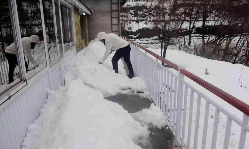 ایبٹ آباد: نتھیا گلی میں شہری گھر کے آگے سے برف ہٹا رہا ہے۔