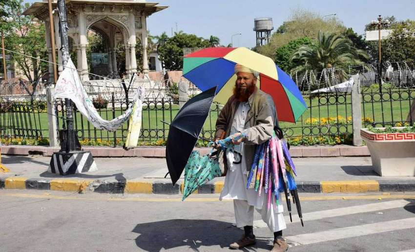 لاہور: ایک محنت کش مال روڈ پر چھتریا فروخت کررہا ہے۔