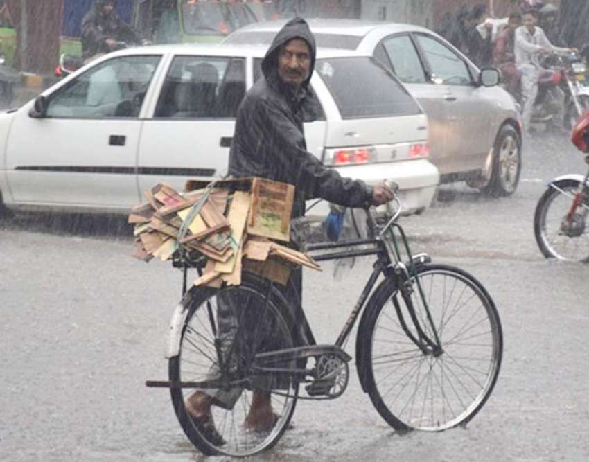 لاہور: ایک شخص شدید بارش میں لکڑی کے کریٹ سیائیکل پر رکھے ..