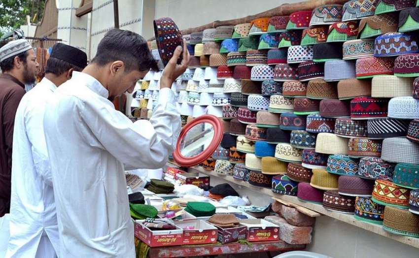 لاہور: شہری سڑک کنارے لگے سٹال سے ٹوپی خرید رہاہے ۔
