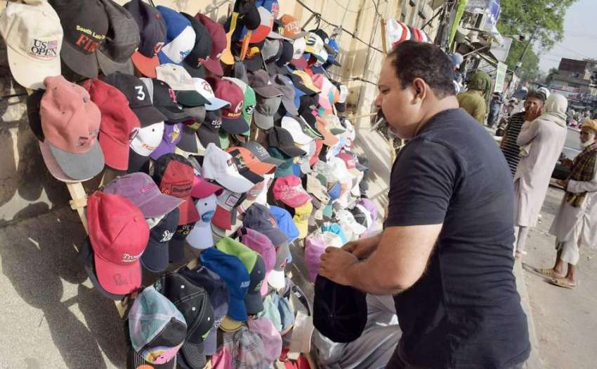 لاہور: ایک شہری دھوپ سے بچنے کے لیے ٹوپی خرید رہا ہے۔