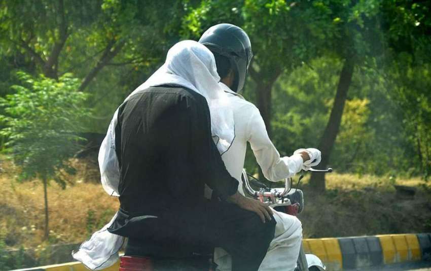 اسلام آباد موٹر سائیکل سوار نے دھوپ کی شدت سے بچنے کے لیے منہ پر کپڑا لے رکھا ہے۔ 