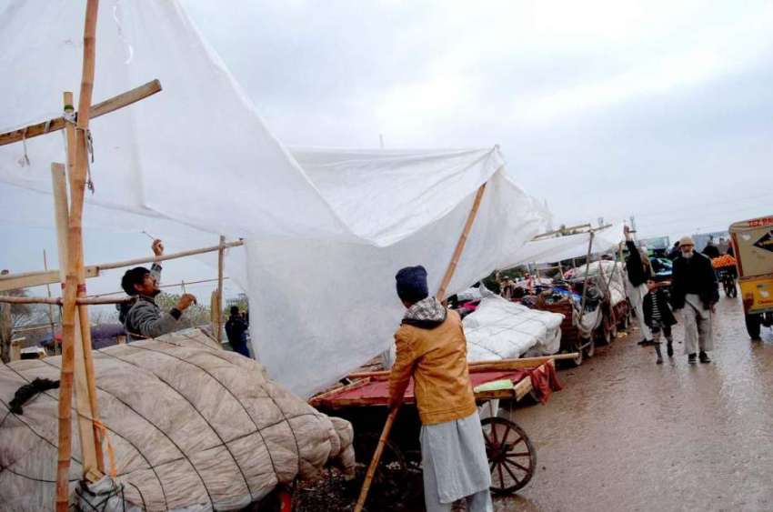 اسلام آباد: ریڑھی بان بارش سے بچاؤ کے لیے اپنی اشیاء پلاسٹک ..