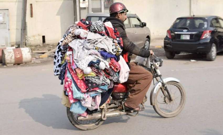 لاہور: ایک موٹر سائیکل سوار لنڈے کے کپڑے فروخت کرنے کے لیے ..