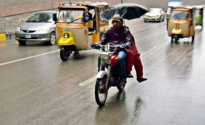 لاہور: موٹر سائیکل سوار بچوں نے بارش سے بچنے کے لیے چھتری ..