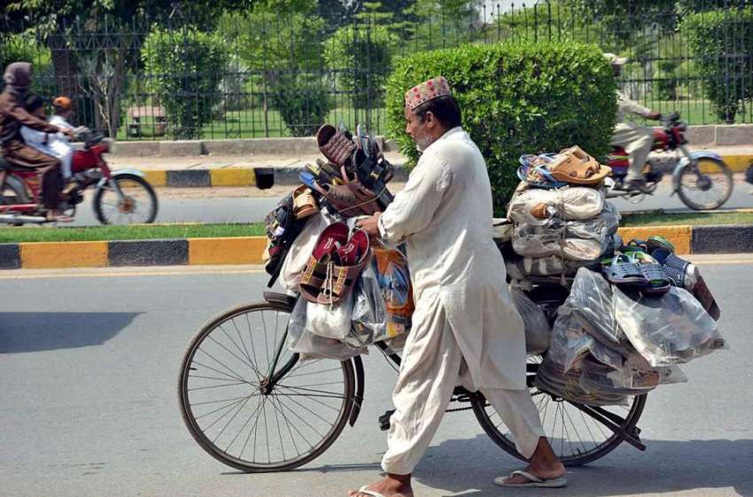 فیصل آباد: محنت کش پھیری لگا کر جوتے فروخت کر رہا ہے۔