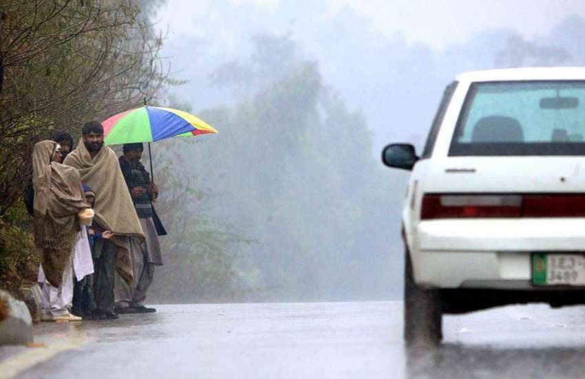 راولپنڈی: شہری موسلا دھار بارش کے دوران بس سٹاپ پر کھڑی بس ..