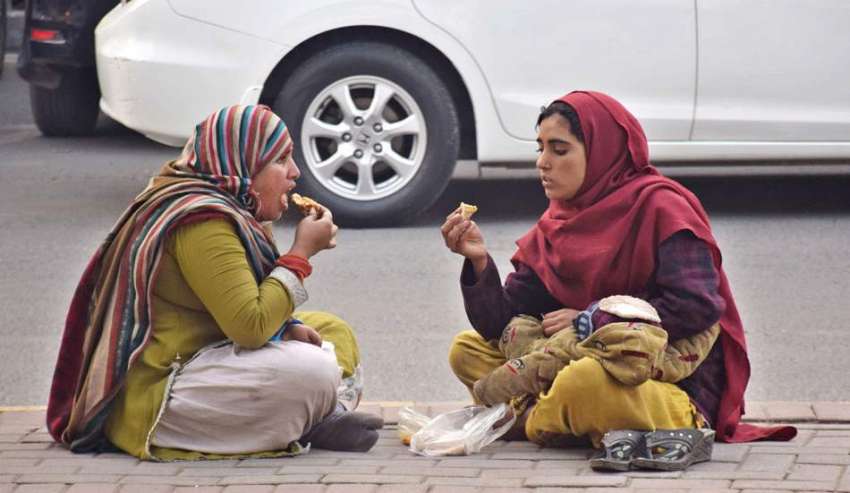 لاہور: بھکاری خواتین ڈیوائیڈر پر بیٹھے کھانا کھارہی ہیں۔ ..