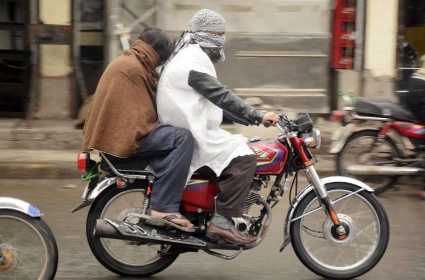 لاہور: موٹرسائیکل سوار بارش کے دوران اپنی منزل کی جانب رواں ..