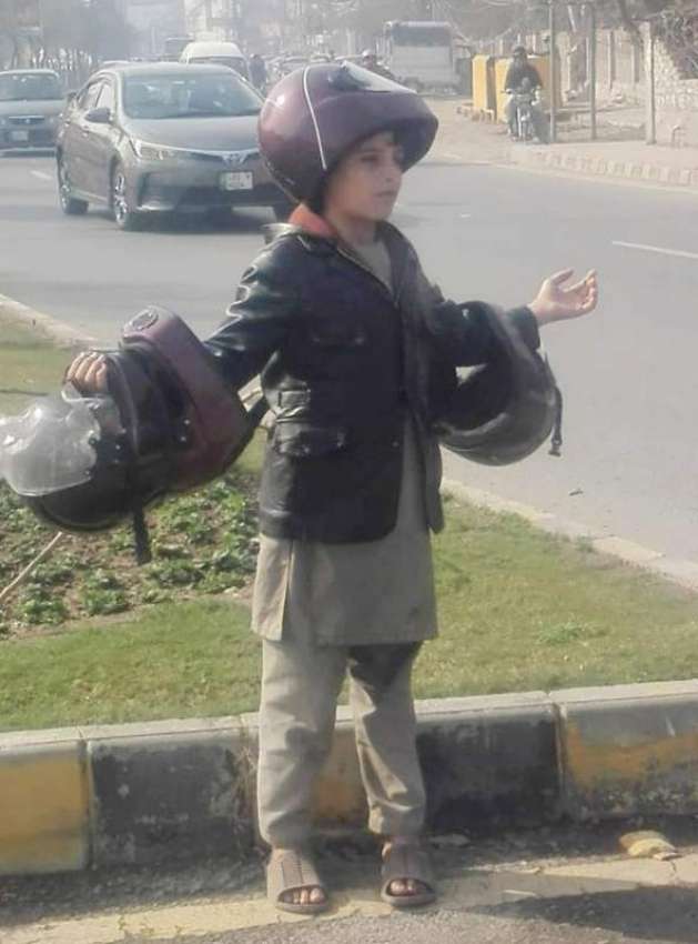 لاہور: ایک بچہ چائنہ چوک میں ہیلمٹ فروخت کرنے کے لیے کھڑا ..