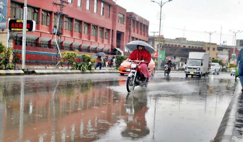راولپنڈی: موٹر سائیکل سوار بارش سے بچنے کے لیے چھتری تانے ..