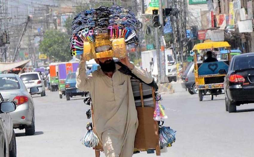 راولپنڈی: ایک محنت کش سر پر مختلف اشیاء اٹھائے فروخت کے لیے ..
