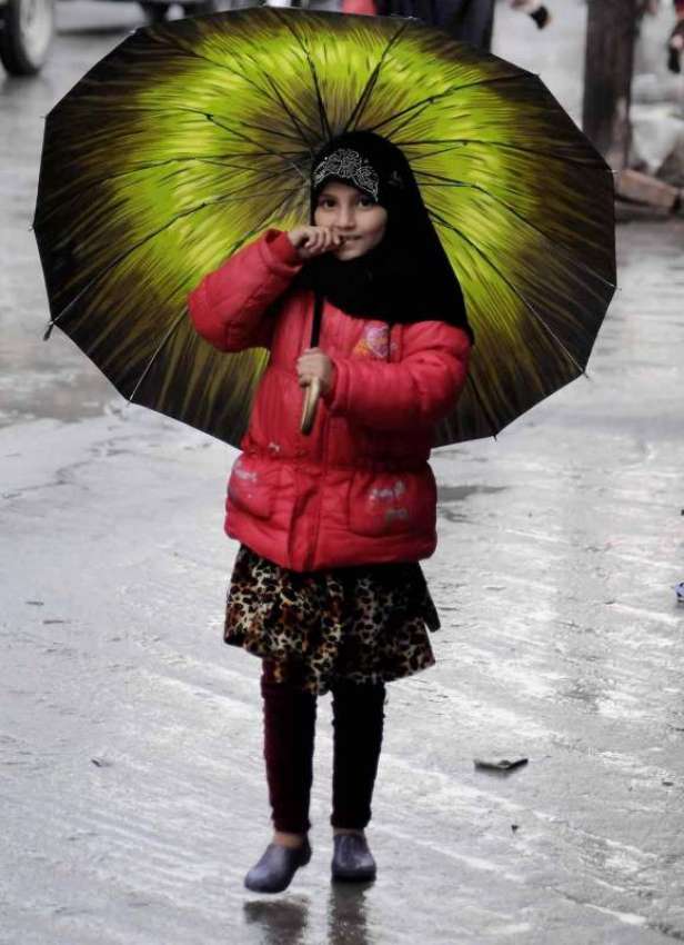 اسلام آباد: کمسن بچی نے بارش سے بچنے کے لیے چھتری تان رکھی ..