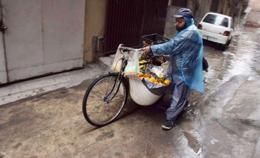 لاہور: ایک پھیری والے نے بارش سے بچنے کے لیے شاپنگ بیگ کو ..