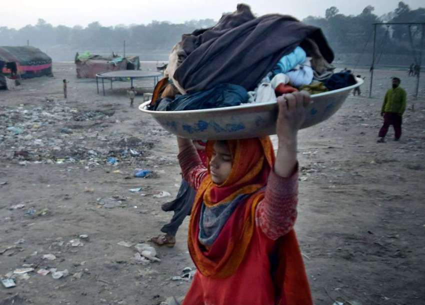 لاہور: دریائے راوی کے کنارے خانہ بدوش بچی کپڑے دھونے کے بعد ..