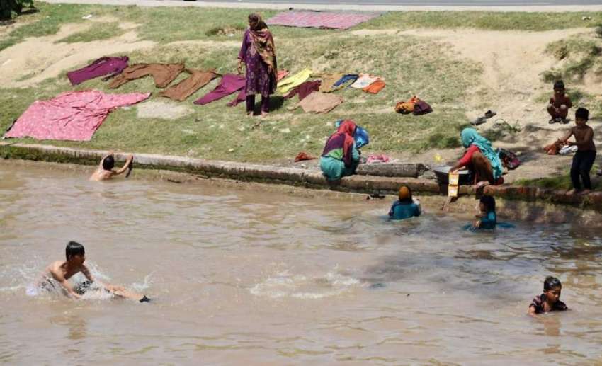 لاہور: خانہ بدوش خواتین نہر کنارے کپڑے دھو رہی ہیں جبکہ بچے ..