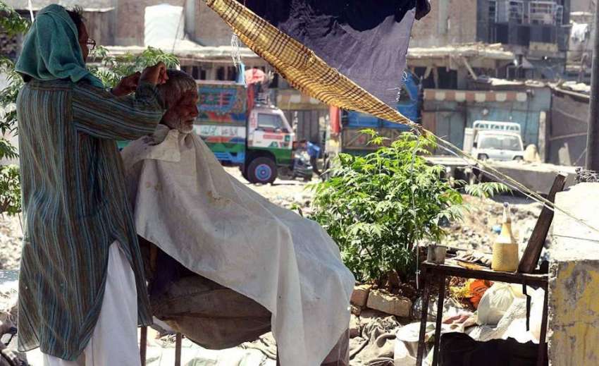 راولپنڈی: شہری سڑک کنارے حجام سے بال کٹوا رہا ہے۔