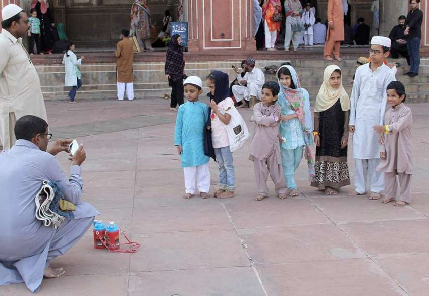 لاہور: بادشاہی مسجد کے احاطے میں ایک شہری موبائل پر بچوں ..