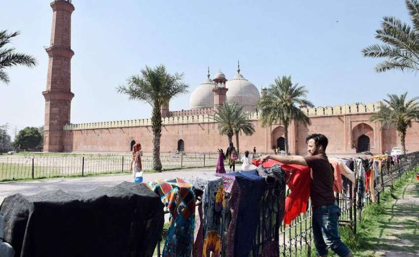 لاہور: ایک نوجوان کپڑے خشک کرنے کے لیے بادشاہی مسجد کے جنگلے ..