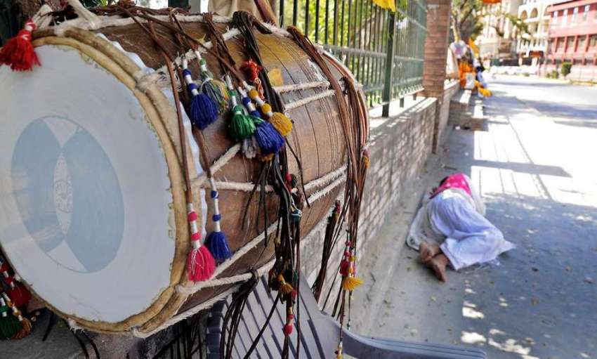 راولپنڈی: ڈھولچی فٹ پاتھ پر دیوار کے سائے میں اپنی نیند پوری ..
