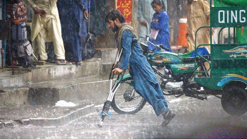 راولپنڈی: بارش کے دوران سڑک عبور کرتا ہوا ایک معذور شخص 
