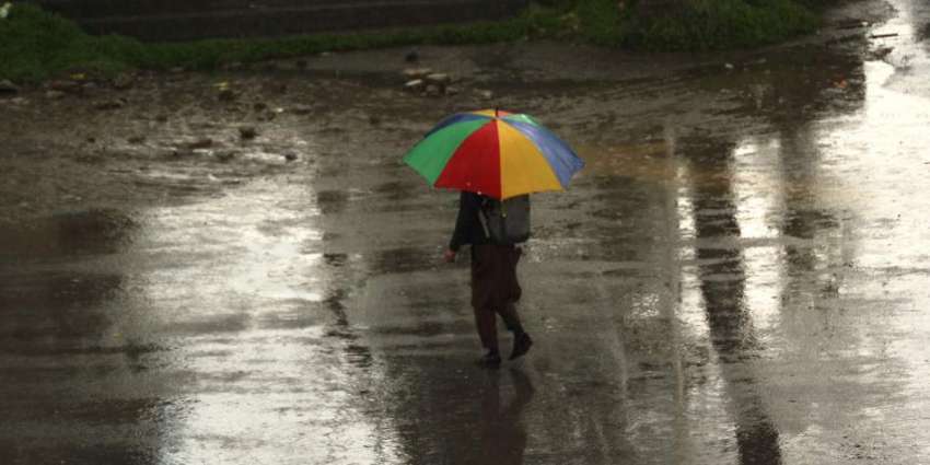 اسلام آباد: نوجوان بارش سے بچنے کے لیے چھتری تانے جارہا ہے۔