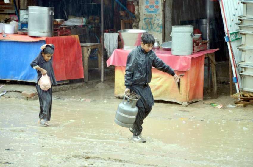 ڈیرہ اللہ یار: ایک بچہ بارش کے دوران گیس کا سلنڈر اٹھائے ..
