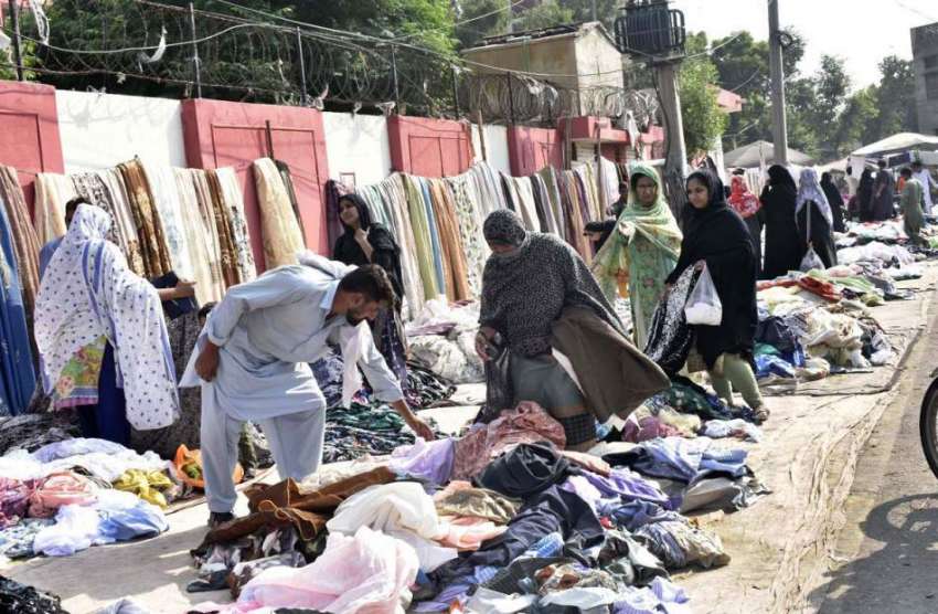 فیصل آباد: خواتین سڑک کے کنارے دکاندار سے کپڑے خرید رہی ہیں۔
