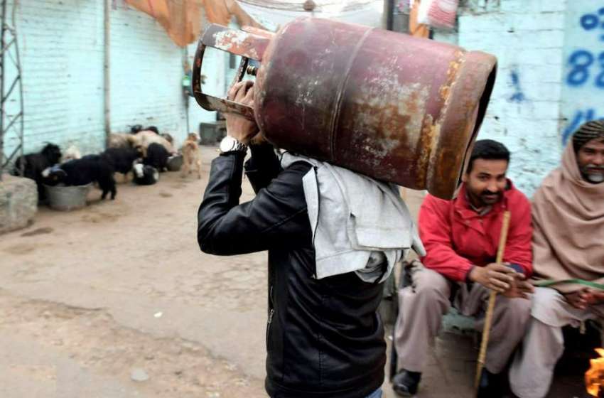 لاہور: ایک شخص بھاری سلنڈر اٹھائے گیس بھروانے کے لیے جارہا ..