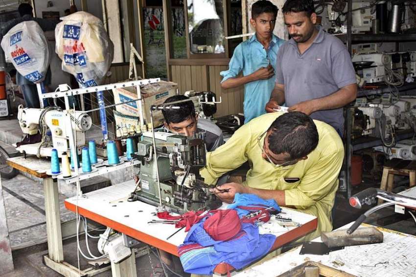 فیصل آباد: مکینک ایمبرائیڈری مشینن کو مرمت کر رہا ہے۔