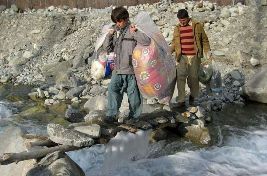 گلگت: ایک شخص اپنے بچے کے ہمراہ سامان اٹھائے دریا کا پل کراس ..