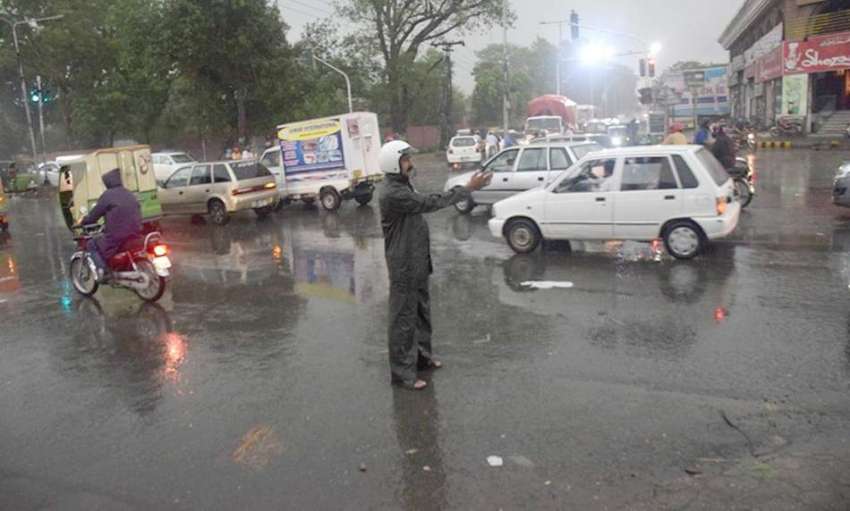 لاہور: ایک ٹریفک وارڈن بارش میں ٹریفک کنٹرول کر رہا ہے۔