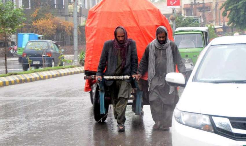 راولپنڈی:بارش کے دوران کام میں مصروف مزدوروں نے سامان کوشیٹ ..