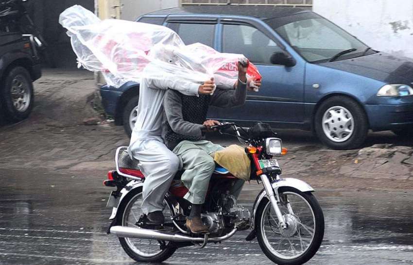 ملتان:  بارش سے بچنے کے لئے موٹرسائیکل سوار  پلاسٹک کی چادر ..